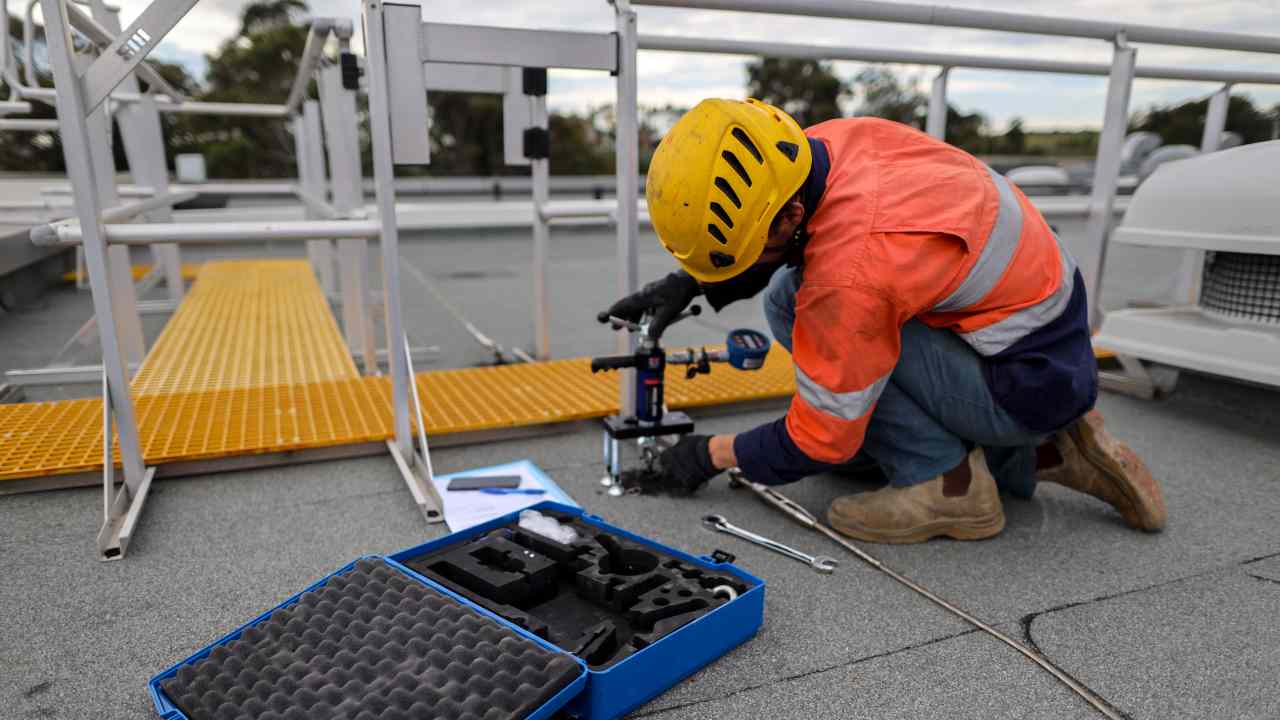 Inspector testing concrete roof anchor point 